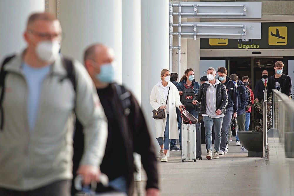 Passengers wearing face masks arrive at Palma de Mallorca Airport on the Spanish Balearic Island of Mallorca, Spain, Saturday, March 27, 2021. Efforts in Spain to restart tourism activity is drawing a mixed picture due to a patchwork of national, regional and European rules on travel that is confusing both tourists and their hosts. (AP Photo/Francisco Ubilla)