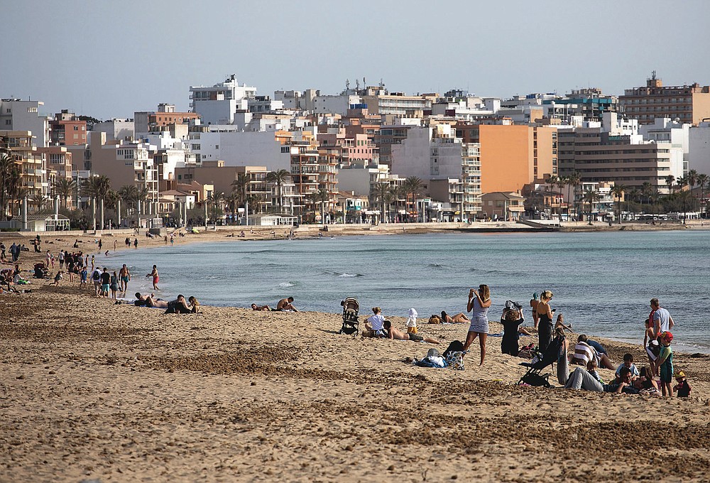 Tourists enjoy the beach at the Spanish Balearic Island of Mallorca, Spain, Monday, March 29, 2021. Efforts in Spain to restart tourism activity is drawing a mixed picture due to a patchwork of national, regional and European rules on travel that is confusing both tourists and their hosts. (AP Photo/Francisco Ubilla)