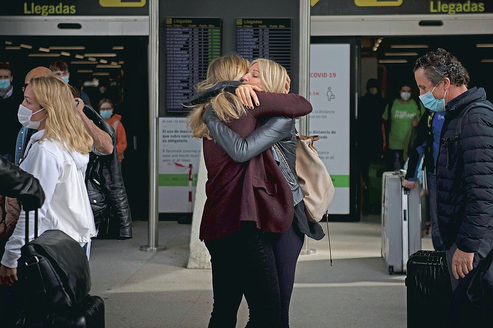 Two women meet at Palma de Mallorca Airport on the Spanish Balearic Island of Mallorca, Spain, Saturday, March 27, 2021. Efforts in Spain to restart tourism activity is drawing a mixed picture due to a patchwork of national, regional and European rules on travel that is confusing both tourists and their hosts. (AP Photo/Francisco Ubilla)