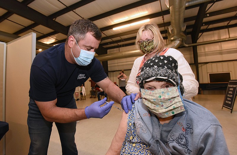 Donna Marshall (center) and her mom, Frances Andrews, get their shots of the Pfizer covid-19 vaccine on Wednesday from Matt Taylor during the first of 13 vaccination clinics to be held each week at the Benton County Fairground auditorium, 7640 SW Regional Airport Blvd. Around 1,000 shots will be administered at each clinic, said Matt Waddle, director of emergency management for Benton County. The next clinic will be April 7. Benton County administration and Collier Drug Stores have teamed up to host the vaccination events. Shots are by appointment only. Call 479-935-4316 to schedule an appointment or visit https://bit.ly/39iawND. People should bring identification and an insurance card to the clinics. Entrance to the clinics is on Arkansas 12. Go to nwaonline.com/210401Daily/ to see more photos.
(NWA Democrat-Gazette/Flip Putthoff)