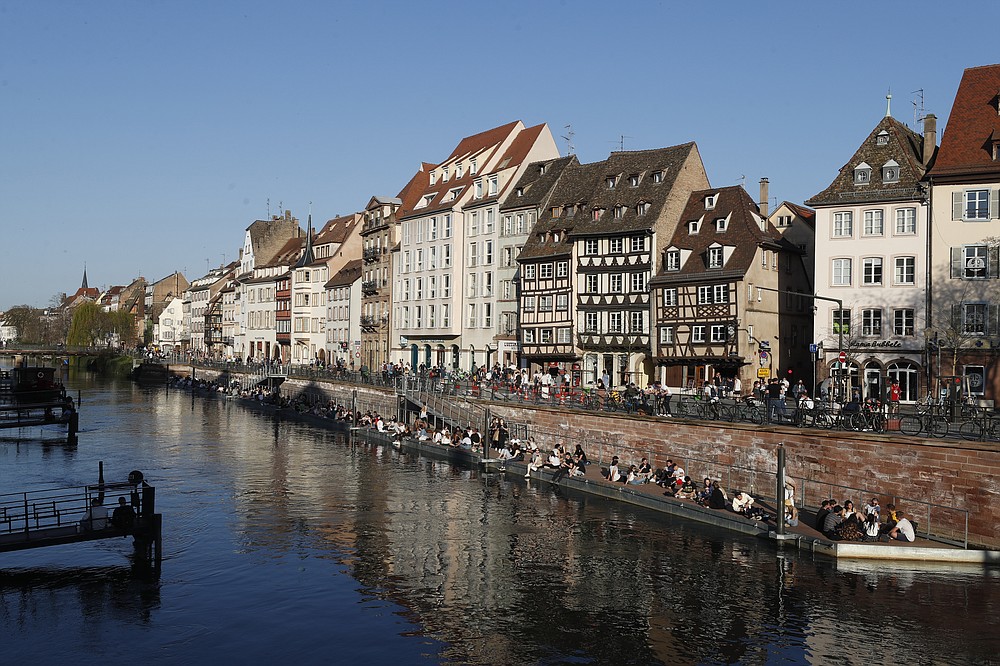 Youths gather along the Ill riverbanks in Strasbourg, eastern France, Wednesday, March 31, 2021. French President Emmanuel Macron is expected to impose new virus restrictions in a televised address to the nation Wednesday night, amid growing pressure to act more boldly to combat surging coronavirus hospitalizations. (AP Photo/Jean-Francois Badias)