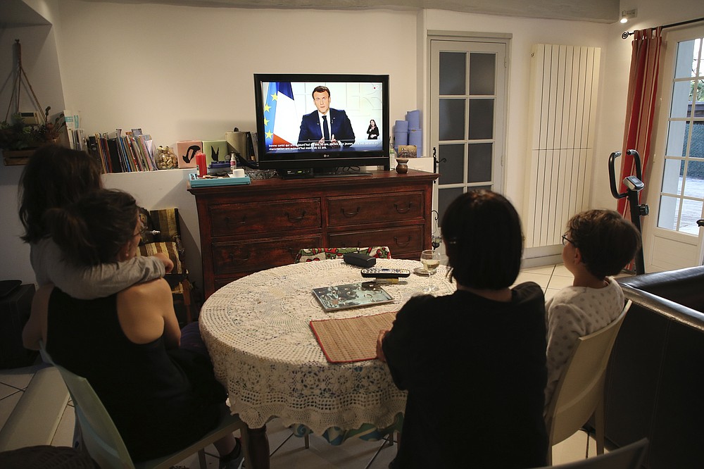 The Larragana family watch French President Emmanuel Macron addressing the nation in Ascain, southwestern France, Wednesday, March 31, 2021. French President Emmanuel Macron is expected to impose new virus restrictions in a televised address to the nation Wednesday night, amid growing pressure to act more boldly to combat surging coronavirus hospitalizations. (AP Photo/Bob Edme)