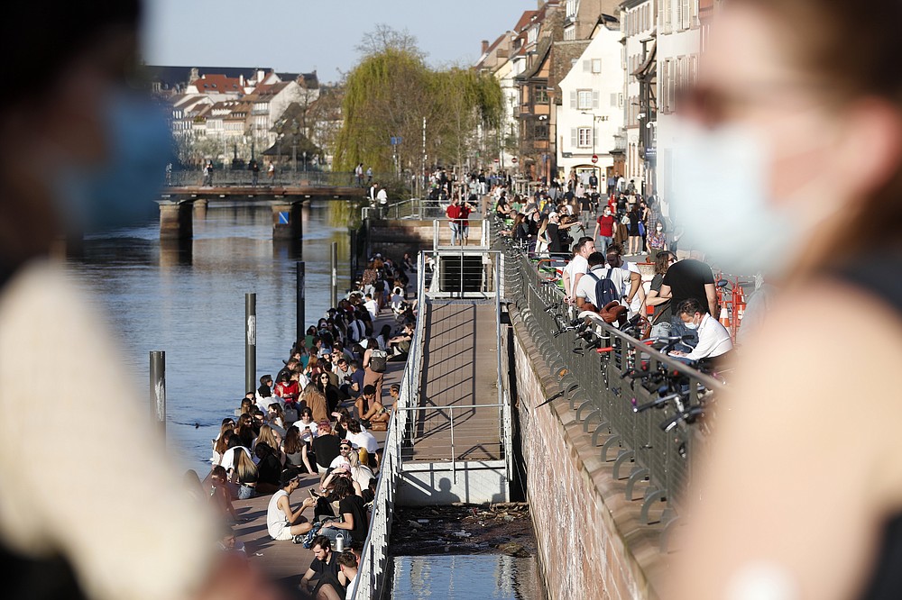 Youths gather along the Ill riverbanks in Strasbourg, eastern France, Wednesday, March 31, 2021. French President Emmanuel Macron is expected to impose new virus restrictions in a televised address to the nation Wednesday night, amid growing pressure to act more boldly to combat surging coronavirus hospitalizations. (AP Photo/Jean-Francois Badias)