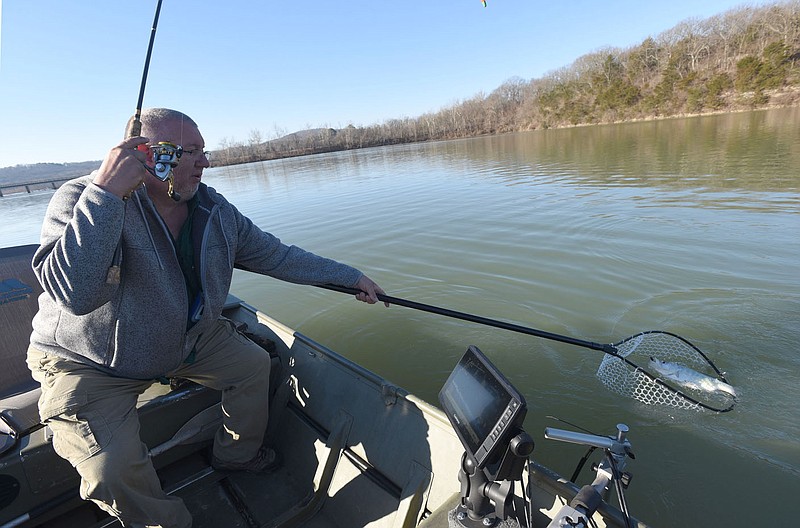 Mike McBride comes prepared with a net to land big crappie at Lake Sequoyah in Fayetteville. Small silver and black jigs rigged three feet under a float on March 4 2021 did the trick. McBride has been fishing at Lake Sequoyah since he was a boy. 
(NWA Democrat-Gazette/Flip Putthoff)