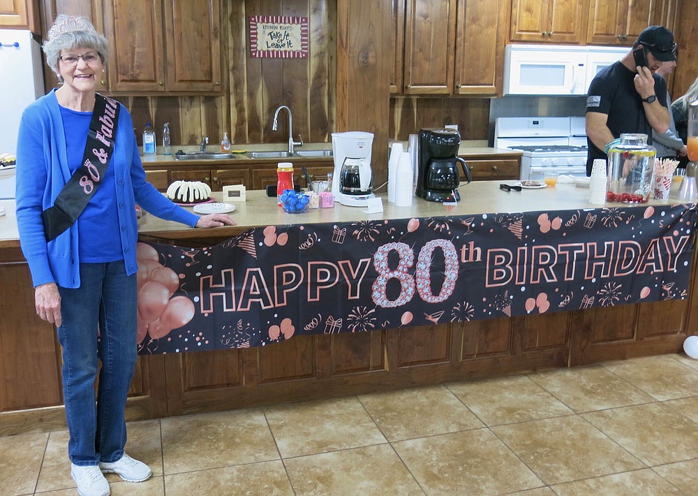 Westside Eagle Observer/SUSAN HOLLAND
Jeanie Easley, of Gravette, shows off the banner wishing her a "Happy 80th Birthday" Wednesday evening, March 13, at the First Baptist Church. Easley was treated to a surprise 80th birthday party by her daughter and son-in-law, Carla and David Bailey, who invited her out to eat for the evening. Several friends and family members came out to help her celebrate with snacks and drinks, birthday cake, gifts and cards.