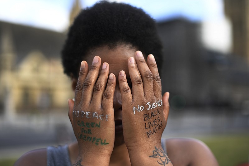 FILE - In this file photo dated Sunday, June 21, 2020, a woman symbolically covers her eyes as she participates in a Black Lives Matter protest calling for an end to racial injustice, at the Parliament Square in central London.  A government inquiry, by a panel of experts, has concluded Wednesday March 31, 2021, that there is racism in Britain, but it’s not a systematically racist country that is “rigged” against non-white people, though many ethnic-minority Britons greeted that claim with skepticism.  (AP Photo/Alberto Pezzali)