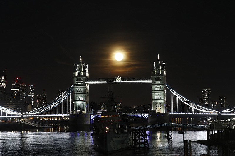 The moon rises over Tower Bridge in London, Monday, March 29, 2021. After enduring three national lockdowns, attractions and hospitality businesses in London are making tentative plans to reopen from mid-May. But deep uncertainty about the coronavirus remains. With quarantine requirements and travel restrictions still in place everywhere and Europe battling a new surge of infections, many are bracing for another bleak year. (AP Photo/Alastair Grant)