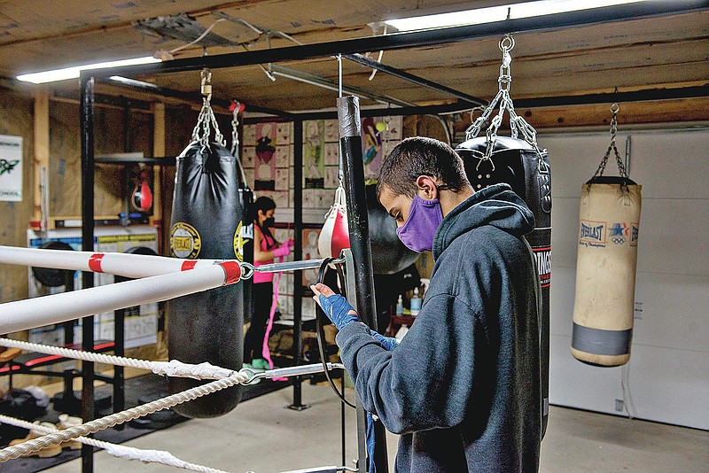 Alex Mazzarisi, 19, wraps his hands at the start of a training session at his father Steve's boxing club in Sterling, Ill. Alex, who started boxing at age 7, took a bit of a hiatus due to a death in the family but has restarted his work in the ring with eyes on eventually going pro. (Alex T. Paschal/The Daily Gazette via AP)