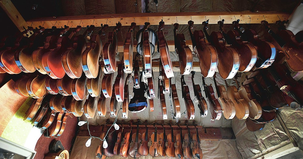 Violins hang from the ceiling outside of Robert Gordon's workshop in Belsano, Pa., on Monday, March 22, 2021. Gordon can hear, and even see, the music inside a piece of wood before he transforms it into a finished violin. To demonstrate how, Gordon, a second-generation luthier, twisted a Douglas fir top to a violin made based on a Guarneri mold that was handed down to him from his father. The wood moved like a wave. (Todd Berkey/The Tribune-Democrat via AP)