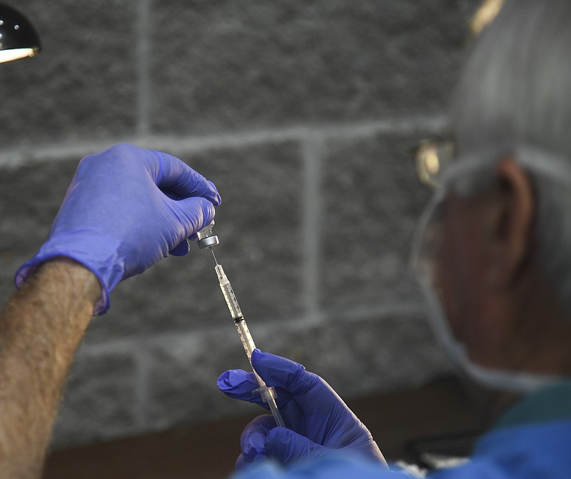 Volunteer Bill Kemp fills a syringe with the Pfizer vaccine during a vaccination clinic hosted by Cooperative Christian Ministries and Clinic inside the Hot Springs Convention Center on March 25. - File photo by The Sentinel-Record
