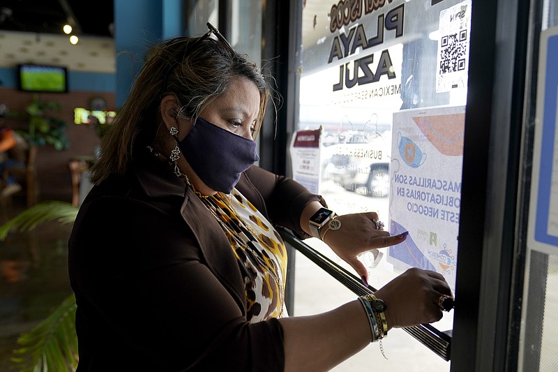 The Associated Press
Irma Chavez hangs up a sign in a grocery store as part of her outreach to the immigrant community, Tuesday, March 9, in Springdale. Chavez came to the United States from her home in El Salvador in 1994 when she was 18 and later was granted temporary protected status.