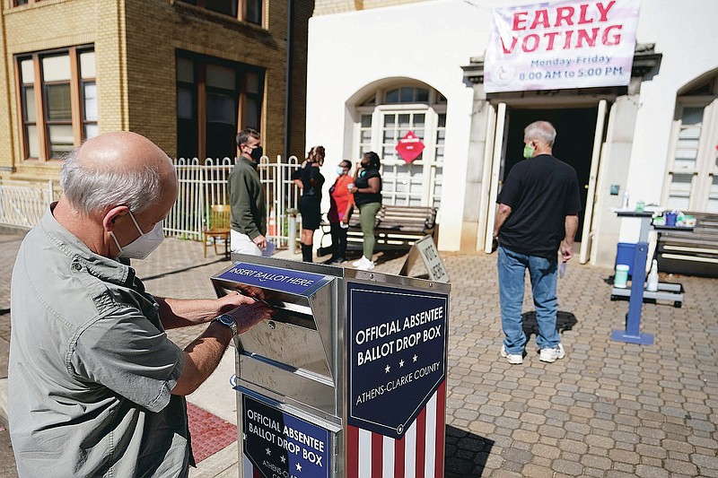 FILE - In this Monday, Oct. 19, 2020 file photo, a voter submits a ballot in an official drop box during early voting in Athens, Ga. On Friday, April 2, 2021, The Associated Press reported on stories circulating online incorrectly asserting “Georgia’s new anti-voting law makes it a jail-time crime to drop off grandma’s absentee ballot in a drop box.” But the election bill known as SB 202, signed into law on March 25, has an exception allowing people to drop off ballots on behalf of their relatives. It also allows a caregiver to deliver a completed ballot on behalf of a disabled person, or a jail employee to deliver a completed ballot on behalf of someone who is in custody. (AP Photo/John Bazemore)