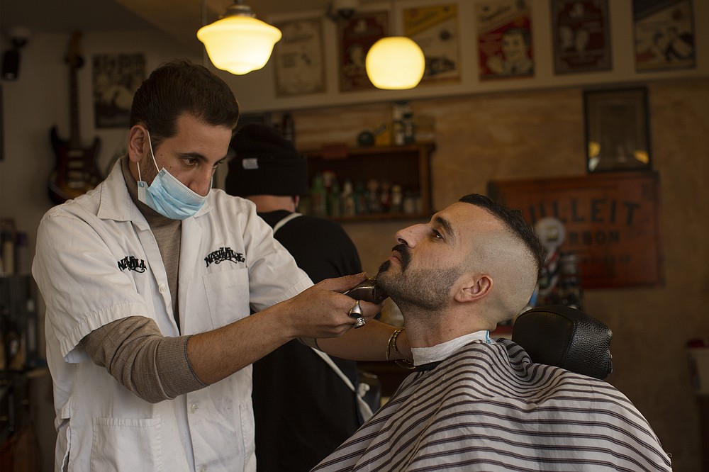 FILE - In this Feb. 23, 2021, file photo, a customer at Nashville Barber Shop gets a shave after coronavirus restrictions were eased in Jerusalem. While Israel provides a glimpse of what may be possible with high immunization rates, it also offers insight into the problems that lie ahead: Workplaces and schools are now grappling with what to do with those who refuse to get vaccinated. (AP Photo/Maya Alleruzzo, File)