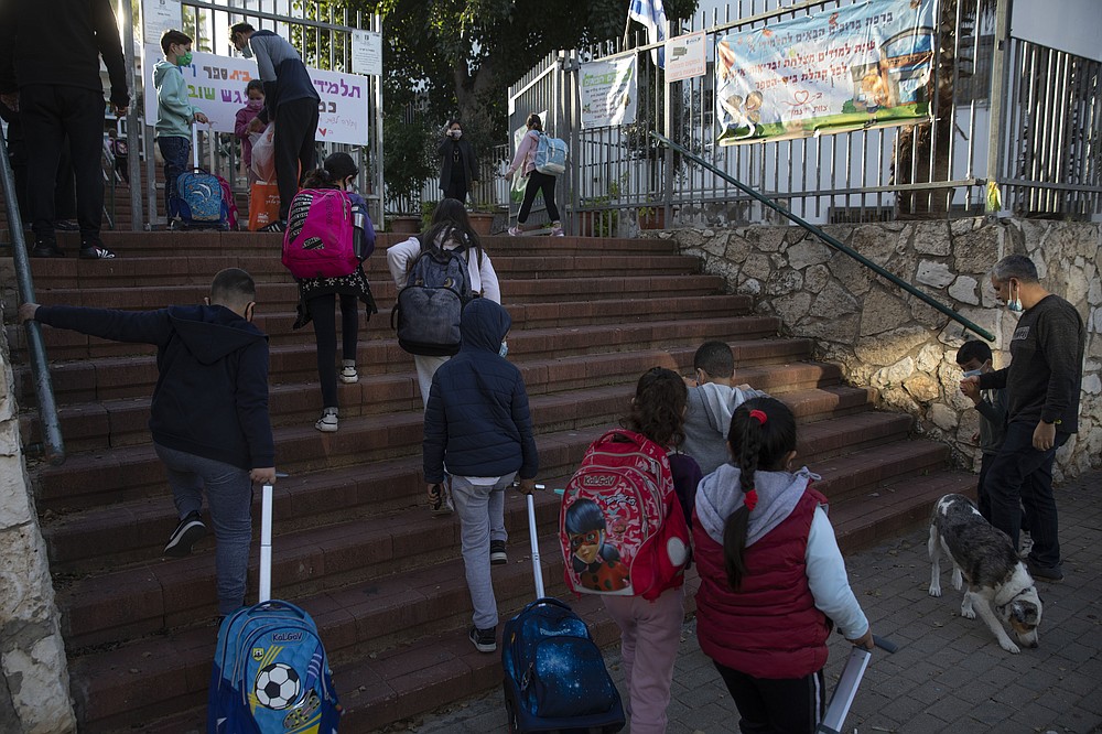 FILE - In this Feb. 11, 2021, file photo, Israeli pupils arrive to school in the central Israeli city of Herzliya. While Israel provides a glimpse of what may be possible with high immunization rates, it also offers insight into the problems that lie ahead: Workplaces and schools are now grappling with what to do with those who refuse to get vaccinated. (AP Photo/Sebastian Scheiner, File)