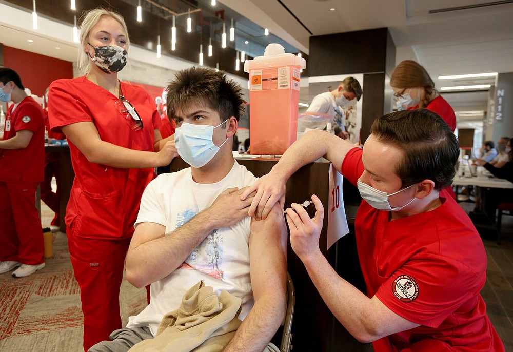 Beck McCall, a junior at the University of Arkansas, receives a covid-19 vaccination shot from Michael Ford, a S1 student in the Eleanor Mann School of Nursing at the University of Arkansas, Thursday, April 1, 2021, during an open covid-19 vaccination clinic hosted by the Northwest Arkansas Council in collaboration with the region's health care systems at Donald W. Reynolds Razorback Stadium on campus in Fayetteville. Check out nwaonline.com/210403Daily/ and nwadg.com/photos for a photo gallery.
(NWA Democrat-Gazette/David Gottschalk)