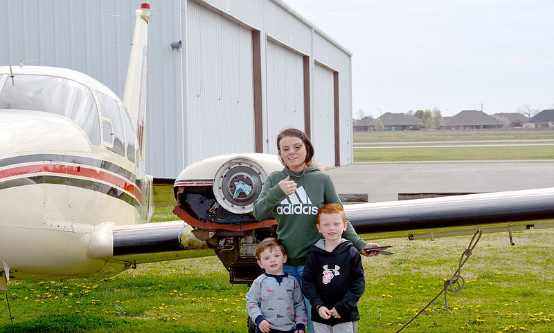 Marc Hayot/Herald-Leader Emily Gregory (center) tries to remove hair from her face while she poses with Cooper Porter and Abel Gregory in front of a plane which was provided for people to come out and look at. People were allowed to touch the plane and pose in front of but were not allowed to go inside.