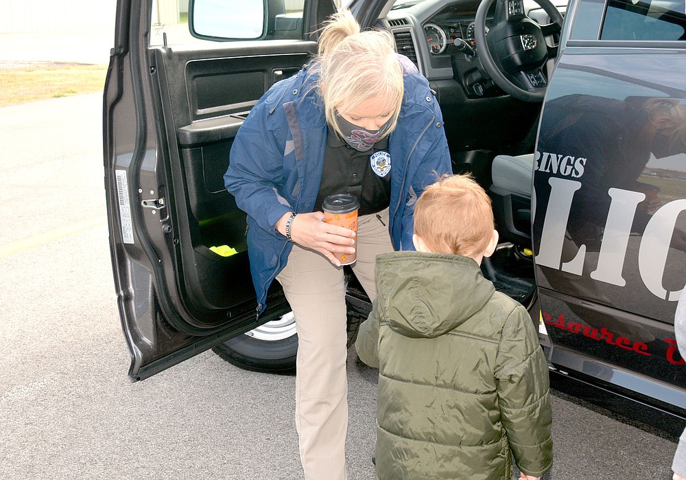 Marc Hayot/Herald-Leader Officer DeAndra Strickland hands Jacob Hughes a magnet, one of two give aways the Siloam Springs Police Department handed out to children on Kite Day.