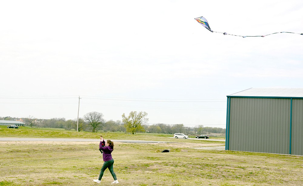 Marc Hayot/Herald-Leader Macie Davis trots down the grass so her kite will fly high. Davis is one of several people who came out to fly their kites on a windy Saturday at the airport where the city held Kite Day.