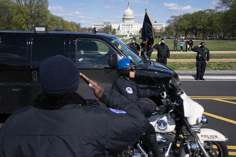 With the U.S. Capitol in the background, U.S. Capitol Police officers salute as procession carries the remains of a U.S. Capitol Police officer who was killed after a man rammed a car into two officers at a barricade outside the Capitol in Washington, Friday, April 2, 2021. (AP Photo/Jose Luis Magana)