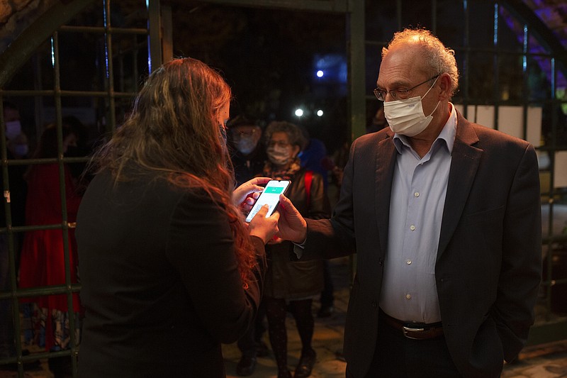 FILE - In this Tuesday, Feb. 23, 2021, file photo, a man presents his "green passport," proof that he is vaccinated against the coronavirus, on opening night at the Khan Theater for a performance where all guests were required to show proof of vaccination or full recovery from the virus, in Jerusalem. Vaccine passports are being developed in the U.S. to verify COVID-19 immunization status and allow inoculated people to more freely travel, shop and dine. (AP Photo/Maya Alleruzzo, File)