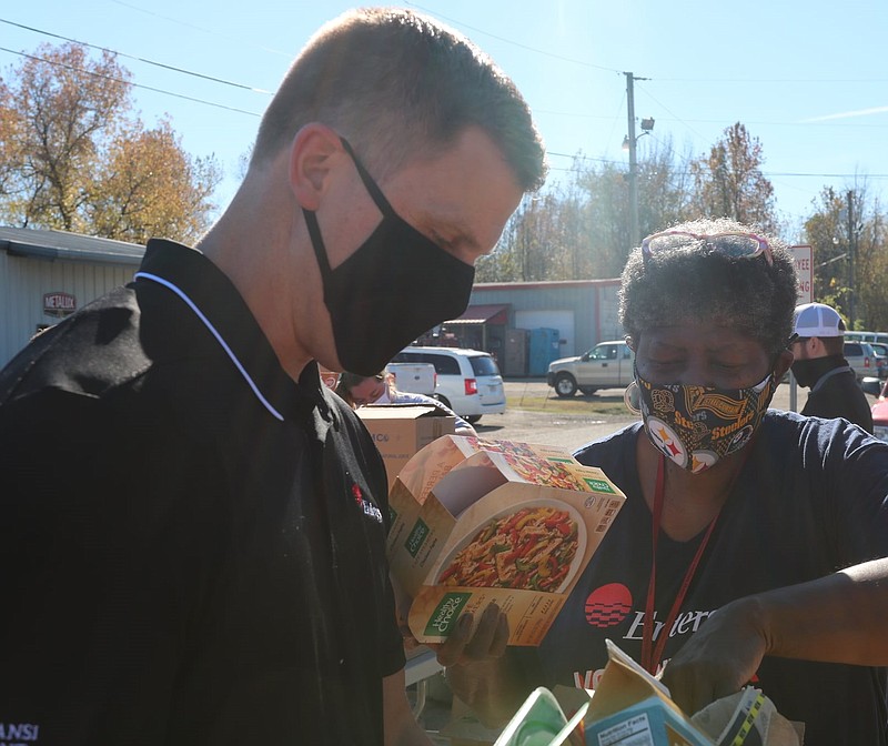 Entergy Arkansas volunteers Jason Oliver, left, with Arkansas Nuclear One and Leticia Finley with Transmission put together boxes of frozen meals, canned goods and shelf-stable items as part of an event with the Arkansas Food Bank in November 2020 to serve veterans in the Russellville area. - Submitted photo