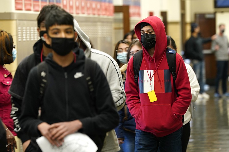 FILE - In this March 31, 2021, file photo, students at Wyandotte County High School wear masks as the walk through a hallway on the first day of in-person learning at the school in Kansas City, Kan. With a massive infusion of federal aid coming their way, schools across the U.S. are weighing how to use the windfall to ease the harm of the pandemic — and to tackle problems that existed long before the coronavirus. (AP Photo/Charlie Riedel, File)