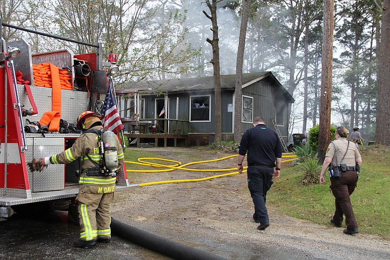 Personnel from 70 West Fire Department and the Garland County Sheriff’s Office work the scene of a fire Sunday evening that destroyed an outbuilding and damaged a house on Warpath Drive. - Photo by Mark Gregory of The Sentinel-Record