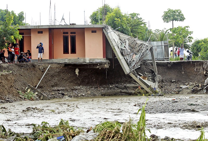 People inspect buildings damaged by a flood in Dili, East Timor, Monday, April 5, 2021. Multiple disasters caused by torrential rains in eastern Indonesia and neighboring East Timor have left dozens of people dead and missing and displaced thousands. (AP Photo/Kandhi Barnez)