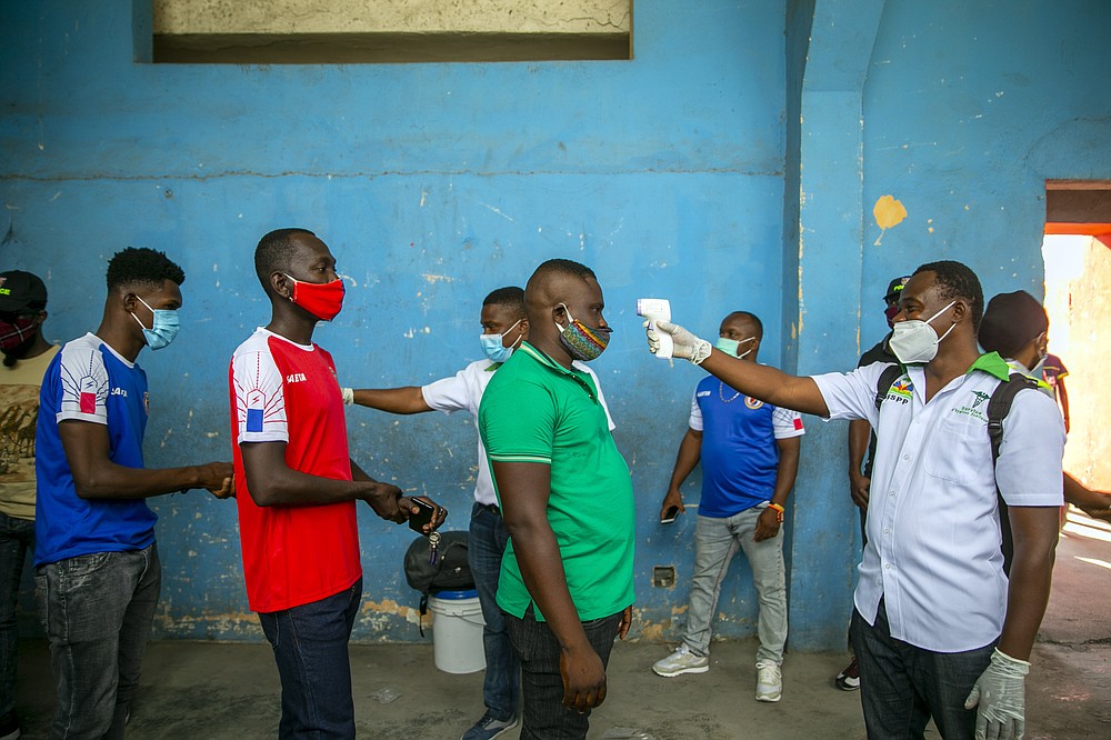 Health ministry workers check the temperature of mask-wearing fans as a precaution against the spread of the new coronavirus, before entering the stadium prior to the start of the CONCACAF World Cup qualifying soccer match between Haiti and Belize in Port-au-prince, Haiti, Thursday, March 25, 2021. ( AP Photo/Dieu Nalio Chery)