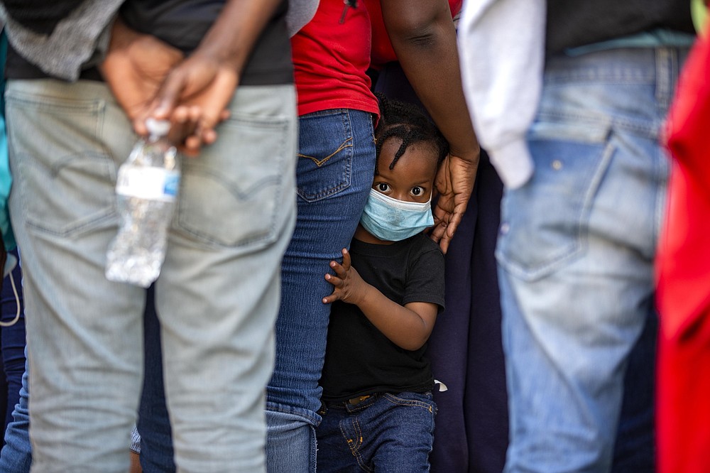 FILE - In this April 23, 2020 file photo, a child looks at the camera as Haitians who were deported from the U.S. line up as they arrive at a hotel where they will be quarantined as a measure against the spread of the new coronavirus in Tabarre, Haiti. (AP Photo/Dieu Nalio Chery, File)