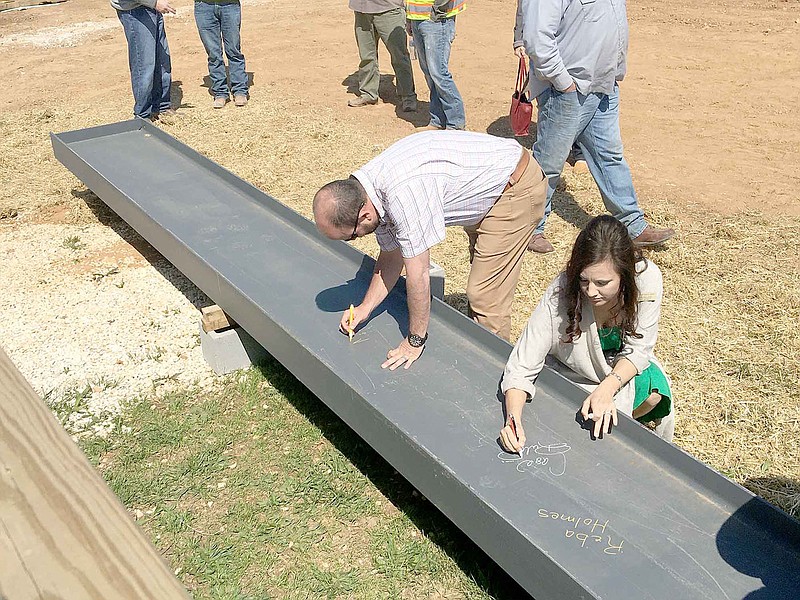 DAVID KELLOGG SPECIAL TO ENTERPRISE-LEADER
Prairie Grove School Board members Casie Ruland and Matt Hargis participate in a topping ceremony for the district's new junior high school. This beam will be the highest point for the new building.