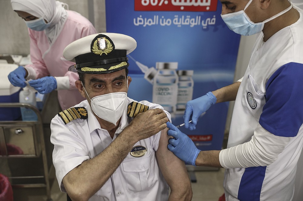 A Suec Cana pilot receives a COVID-19 vaccine in Ismailia, Egypt, Tuesday, April 6, 2021. The Suez Canal chief said Tuesday that authorities are negotiating a financial settlement with the owners of a massive vessel that blocked the crucial waterway for nearly a week. (AP Photo/Mohamed Elshahed)