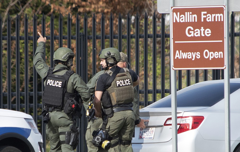 Members of the Frederick Police Department Special Response Team prepare to enter Fort Detrick at the Nallin Farm Gate in a convoy of vans and sedans following a shooting in Riverside Tech Park, near the Royal Farms on Monocacy Boulevard, Tuesday, April 6, 2021, in northeast Frederick, Md. Authorities say a Navy medic shot and critically wounded two people at a Maryland business park before fleeing to the Fort Detrick Army base, where he was shot and killed. (Graham Cullen/The Frederick News-Post via AP)