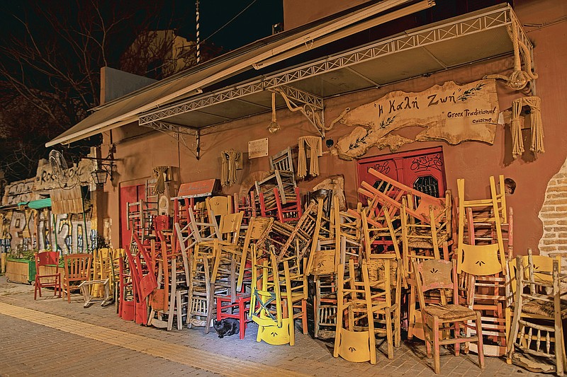 A cat stands near coloured chairs and tables stored outside a closed traditional restaurant in Monastiraki, district of Athens, on Tuesday, March 16, 2021. Restaurants, bars and cafes, whose nature it is to gather groups of people closely together, have remained shut since November when the Greek government imposed a second lockdown to curb the spread of COVID-19 infections. (AP Photo/Petros Giannakouris)