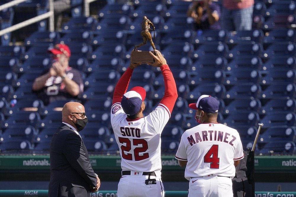 Washington Nationals right fielder Juan Soto (22) holds up his 2020 National League batting title trophy alongside general manager Mike Rizzo, left, and manager Dave Martinez before an opening day baseball game against the Atlanta Braves at Nationals Park, Tuesday, April 6, 2021, in Washington. (AP Photo/Alex Brandon)