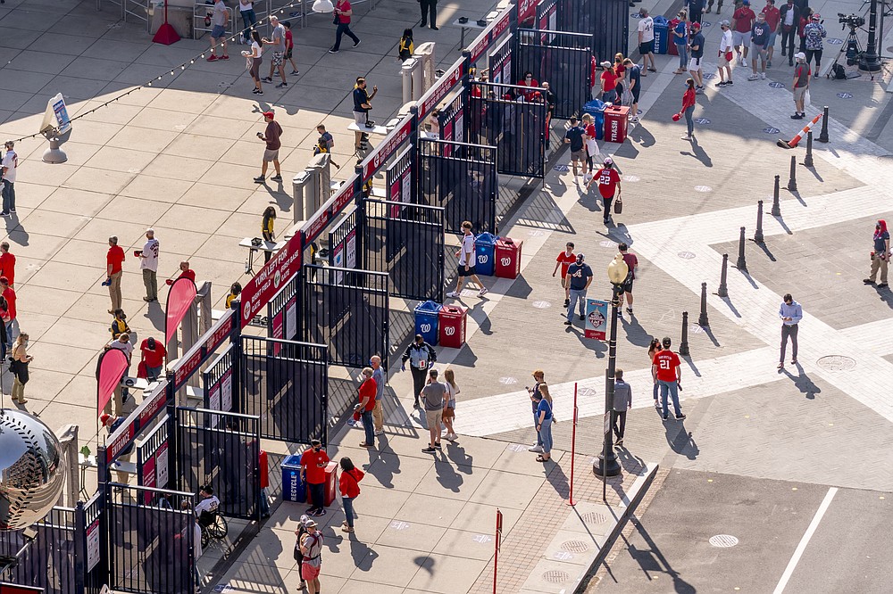 A steady trickle of fans arrive at the centerfield gate as the Washington Nationals play the Atlanta Braves in their opening day baseball game at Nationals Park, Tuesday, April 6, 2021, in Washington. (AP Photo/Andrew Harnik)