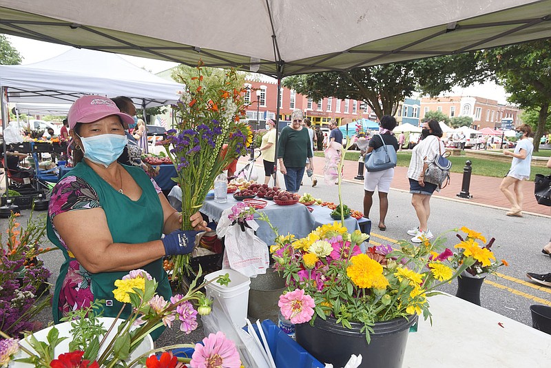 MARKET RETURNS TO SQUARE
Pa Lao creates flower arrangements on Saturday July 11 2020 in her tent at the Bentonville Farmers Market. Saturday was the first weekend the event has been held on the square since being held this year as a drive-through market at Orchards Park. Customers are welcome to browse on foot for flowers, crafts and food each Saturday. Customers must wear masks. Go to nwaonline.com/200712Daily/
(NWA Democrat/Gazette/Flip Putthoff)