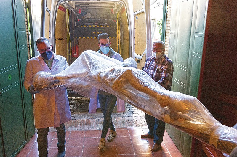 A restored figure of Jesus arrives into Nuestra Senora de la Candelaria church in Seville, southern Spain, Thursday, March 25, 2021. Few Catholics in devout southern Spain would have imagined an April without the pomp and ceremony of Holy Week processions. With the coronavirus pandemic unremitting, they will miss them for a second year. (AP Photo/Laura Leon)