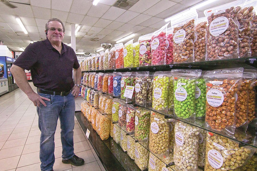 Stephen Canale stands by the wide selection of his gourmet popcorn in Middletown Market, Wednesday, March 17, 2021, in Genoa Township, Mich. The market, which features an entire aisle of It’s So Fluffy popcorn flavors — Canale's up to about 50 different flavors — is among a growing list of local retailers carrying his products. (Gillis Benedict/Livingston County Daily Press & Argus via AP)