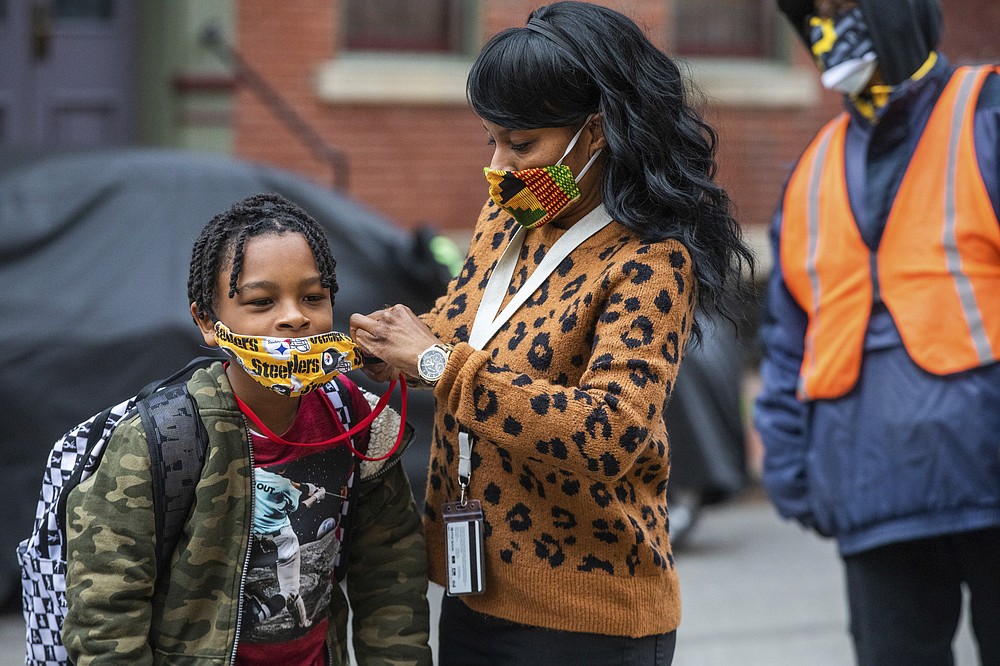 FILE - In this Monday, March 29, 2021, file photo, Jenea Edwards, of the North Side, helps her son Elijah, 9, in the third grade, with his mask before heading into Manchester Academic Charter School on the first day of in-person learning via a hybrid schedule, in Pittsburgh. A new survey from the Biden administration finds that large numbers of students are not returning to the classroom even as more schools reopen for full-time, in-person learning. (Andrew Rush/Pittsburgh Post-Gazette via AP, File)
