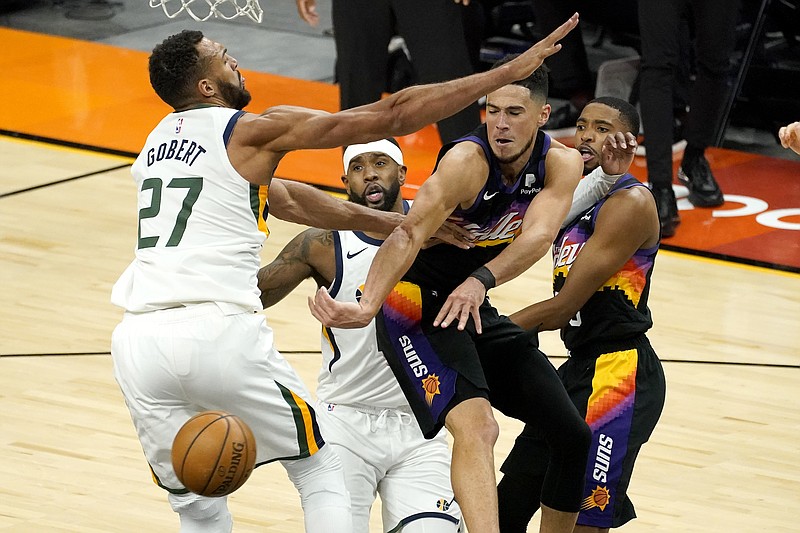Phoenix Suns guard Devin Booker, right, dishes off around Utah Jazz center Rudy Gobert (27) during the first half of Wednesday's game in Phoenix. - Photo by Matt York of The Associated Press