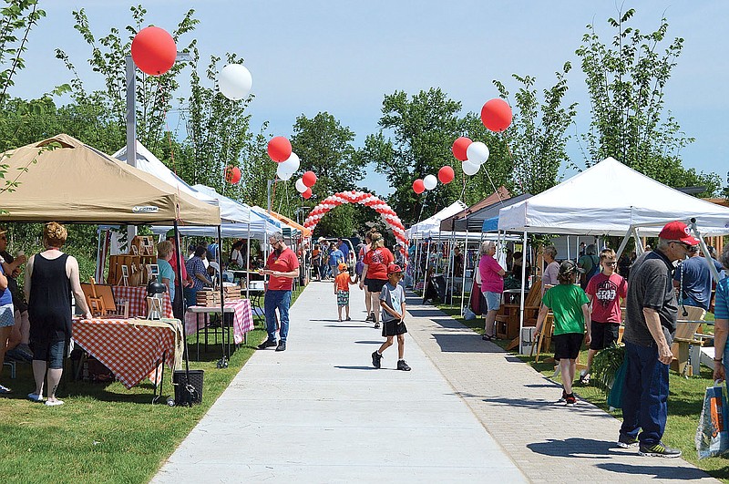File photo
Community members stroll booths and talk with vendors during the Siloam Springs Farmers Market in 2019. This year's outdoor market will open for the season on April 17.