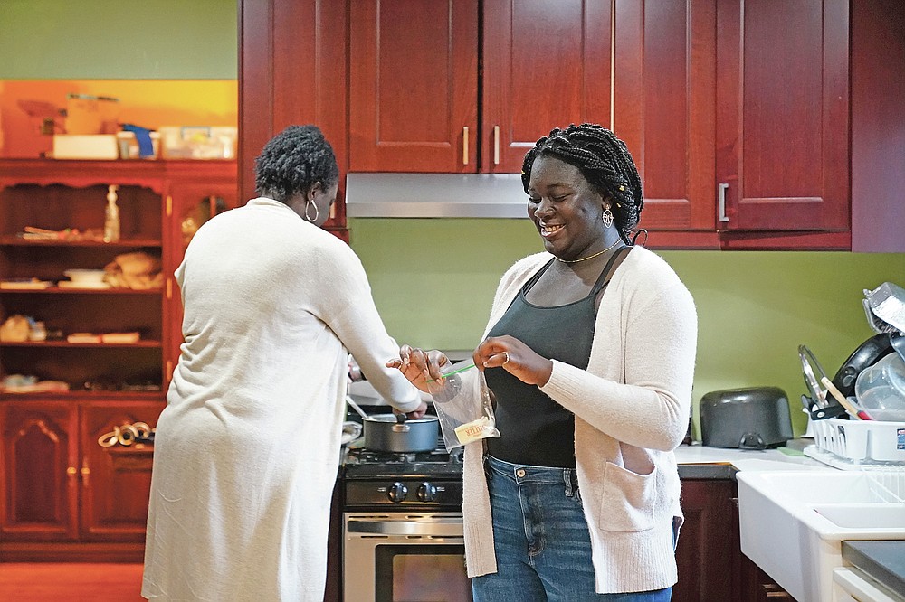 Ebele Azikiwe, 12, right, cooks with her mother, Rume Joy Azikiwe-Oyeyemi, at home in Cherry Hill, N.J., Wednesday, March 24, 2021. Ebele testified in October at state Assembly hearing, lending her support to legislation requiring New Jersey's school districts to add diversity to curriculums. Democratic Gov. Phil Murphy signed the bill into law. (AP Photo/Matt Rourke)