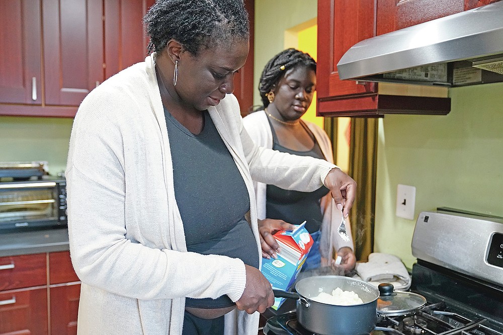 Ebele Azikiwe, 12, right, cooks with her mother, Rume Joy Azikiwe-Oyeyemi, at home in Cherry Hill, N.J., Wednesday, March 24, 2021. Ebele testified in October at state Assembly hearing, lending her support to legislation requiring New Jersey's school districts to add diversity to curriculums. Democratic Gov. Phil Murphy signed the bill into law. (AP Photo/Matt Rourke)