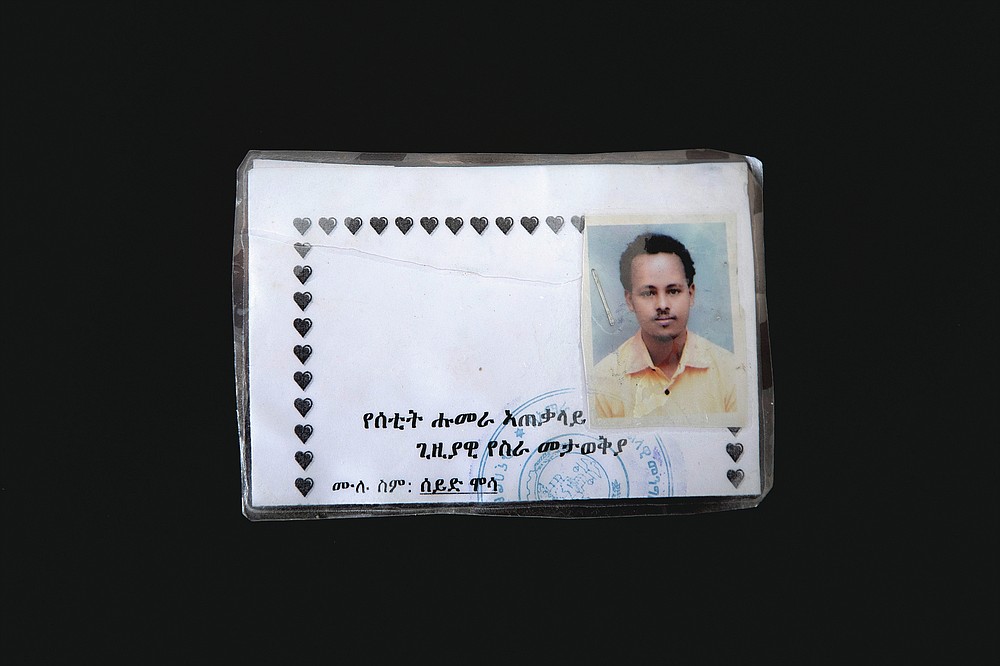 This March 17, 2021 photo shows a new ID card issued by Amhara authorities to Seid Mussa Omar, a 29-year-old Tigrayan nurse from Humera, who fled to Hamdayet, eastern Sudan, near the border with Ethiopia. Amhara authorities took Omar's original ID card displaying his Tigrayan ethnicity and burned it, he said. On the new card examined by the AP, traces of Tigray had vanished. It was issued in January 2021 in a city located so far north in Ethiopia that it is within sight of neighboring Eritrea. Yet the card is stamped by authorities of the Amhara region to the south. The language on the card is Amharic, not the Tigrinya of Tigray. Translation from Amharic reads, "Setit Humera General Temporary Work Place Identity — Full Name: Seid Mussa." (AP Photo/Nariman El-Mofty)