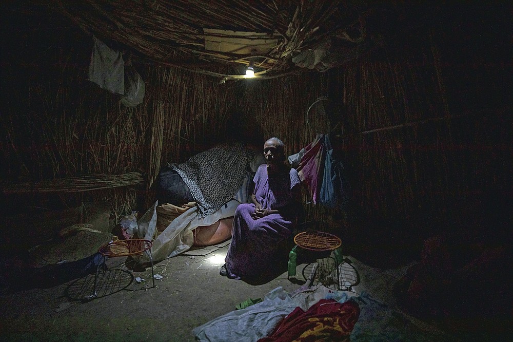 Tigrayan refugee Belaynesh Beyene, 58, who fled the conflict in the Ethiopia's Tigray, sits in her shelter in Hamdayet, eastern Sudan, near the border with Ethiopia, on March 13, 2021. Beyene said she saw 24 bodies in Dansha. "They accidentally killed an ethnic Oromo in a Tigrayan household," she said. "When they realized their 'mistake,' they came and buried him." (AP Photo/Nariman El-Mofty)