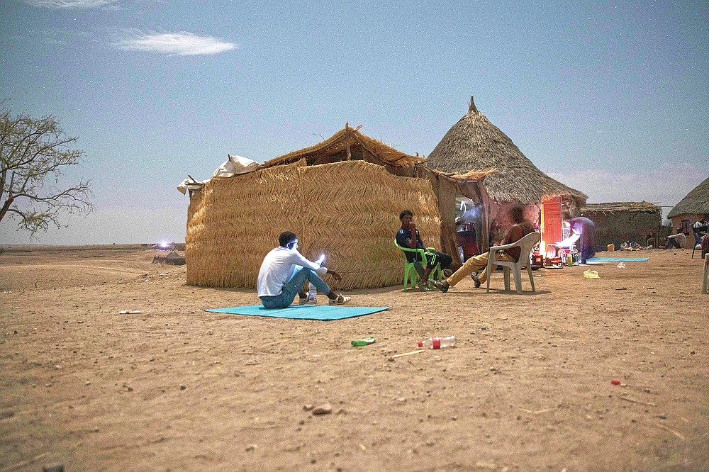 Tigrayan refugees who fled the conflict in the Ethiopia's Tigray try to find a network signal for their mobile phones in Hamdayet, eastern Sudan, near the border with Ethiopia, on March 23, 2021. For months, it has been the Tigrayans' word against that of the government in Ethiopia, Africa's second most populous country and one of its most powerful. But now, for the first time, there is official proof of what is being called ethnic cleansing in the form of identity cards smuggled across the border into this Sudanese border post and confirmed to The Associated Press by more than a half-dozen refugees from different communities. (AP Photo/Nariman El-Mofty)