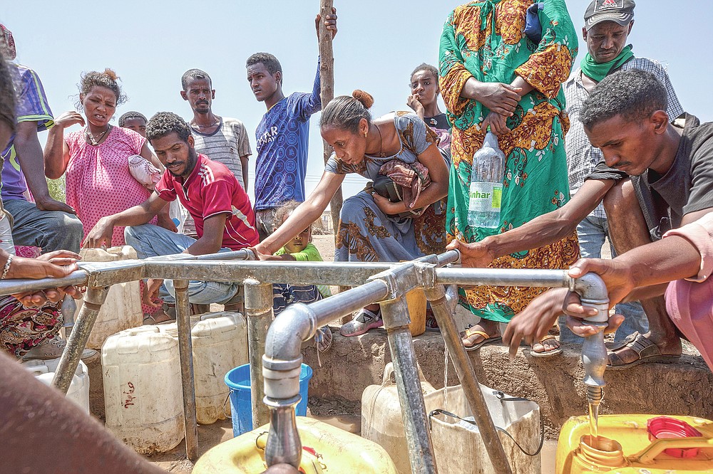 Elsa Tesfa Berhe, 26, center, a reproductive health official from Adwa, collects water a day after arriving from Humera to Hamdayet, eastern Sudan, near the border with Ethiopia, on March 16, 2021. Reusing gloves and rationing water, Berhe treated women secretly after Eritrean soldiers swept through health centers, looting even the beds and telling patients to leave. As she snuck out to deliver babies and treat the wounded, she saw people trying to bury bodies at the risk of being shot, or pouring alcohol on corpses in an attempt to hide the smell. (AP Photo/Nariman El-Mofty)