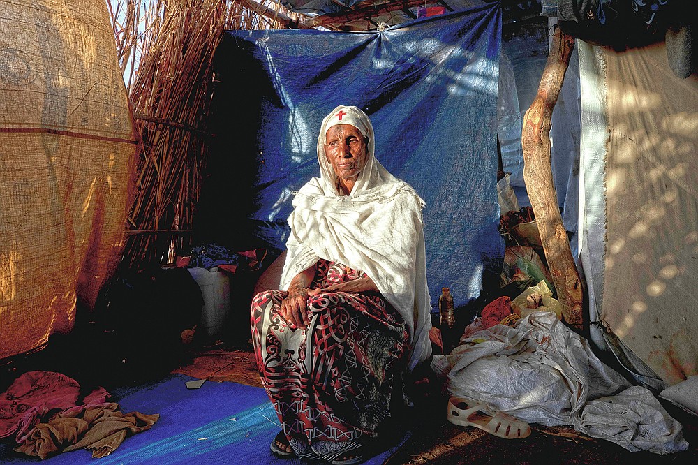Tigrayan refugee Maza Girmay, 65, sits in her shelter, in Hamdayet, eastern Sudan, near the border with Ethiopia, on March 15, 2021. "I heard food was being distributed," she said. She went to the government office in her community of Bahkar to inquire. "They told me, 'Go home, you're Tigrayan.'" The rejection brought her to tears. "We Tigrayans are Ethiopian. Why do they treat us as non-Ethiopian?" she said. (AP Photo/Nariman El-Mofty)