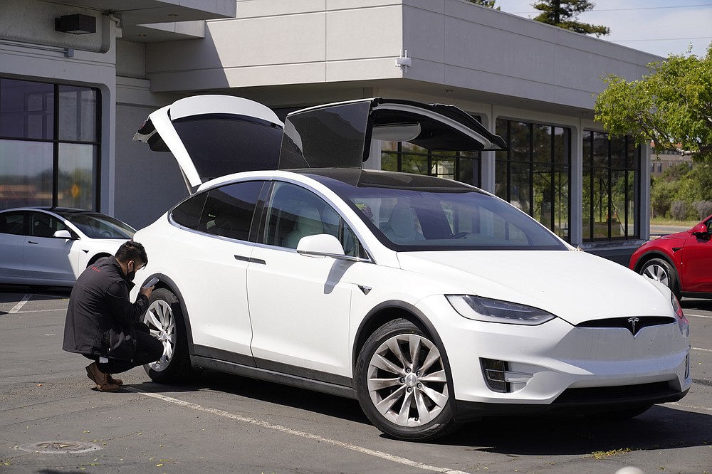 A worker inspects a new electric car at a Tesla delivery location and service center Friday, April 2, 2021, in Corte Madera, Calif. The president and auto industry maintain the nation is on the cusp of a gigantic shift to electric vehicles and away from liquid-fueled cars, but biofuels producers and some of their supporters in Congress aren't buying it and argue now is the time to increase sales of ethanol and biodiesel, not abandon them. (AP Photo/Eric Risberg)